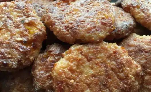Piatto di polpette di patate e zucchine dorate al forno servite con prezzemolo fresco su un vassoio.
