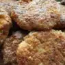Piatto di polpette di patate e zucchine dorate al forno servite con prezzemolo fresco su un vassoio.