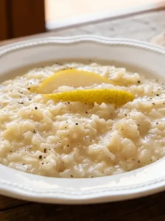 Piatto elegante di risotto cremoso alle pere e gorgonzola decorato con noci e pepe nero