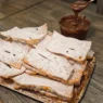 Chiacchiere di Carnevale friabili e piene di bolle spolverate con zucchero a velo su un vassoio