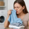 Donna che annusa panni appena lavati con espressione sorpresa per cattivo odore di umido.