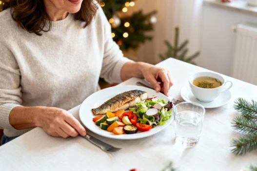 Donna italiana a tavola con dieta leggera prima di Natale: pesce grigliato, verdure e tisana in ambiente natalizio luminoso