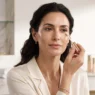 Ritratto di una donna elegante over 40 che applica il correttore, mostrando i passaggi per una base trucco viso impeccabile e luminosa.