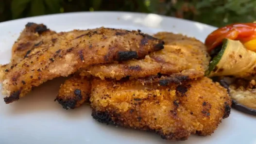 Una cotoletta panata in un piatto con verdure
