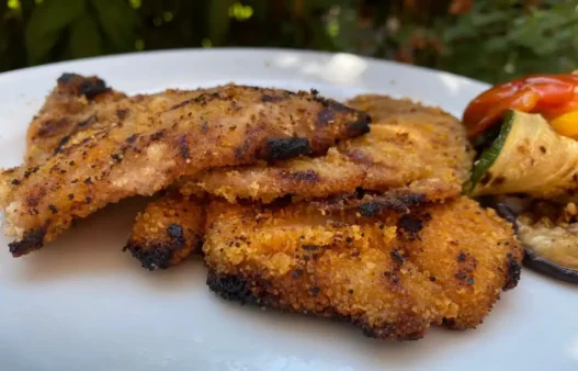 Una cotoletta panata in un piatto con verdure