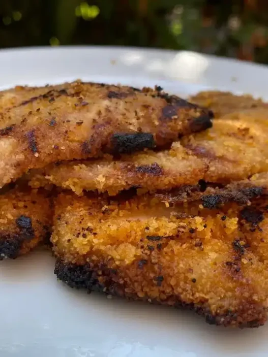 Una cotoletta panata in un piatto con verdure