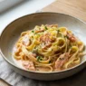 Un piatto di tagliatelle al salmone accompagnato da un calice di vino