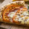 Trancio di sfogliata salata con zucca arancione, fette di speck e taleggio fuso in superficie, cosparso di semi di lino