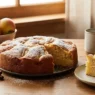 Una torta di mela su un tavolo con delle mele accanto