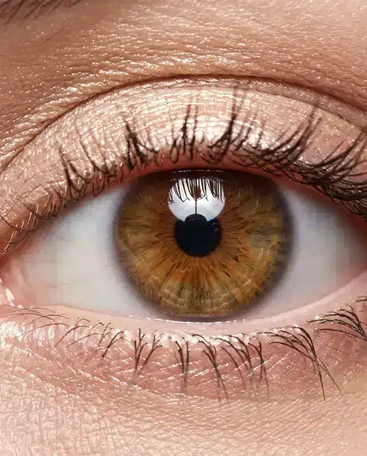Un primo piano macro di un occhio femminile spalancato e luminoso, che mostra un trucco studiato per ingrandirlo con matita chiara nella rima interna e ombretto scintillante.