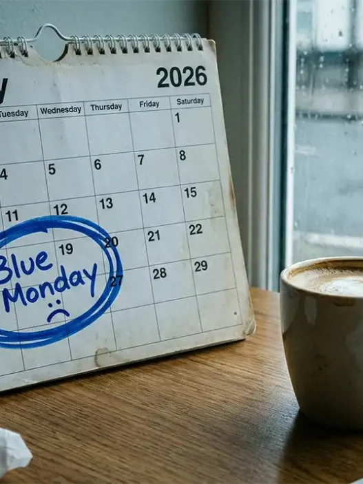 Calendario con la data del terzo lunedì di gennaio cerchiata in blu e una tazza di caffè