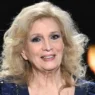 Iva Zanicchi sorridente con un mazzo di fiori, icona della musica italiana