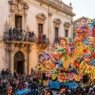 Maestoso carro allegorico in cartapesta sfila tra la folla ad Acireale con luci barocche sullo sfondo