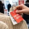 Mano che controlla un cartellino dei saldi su un maglione