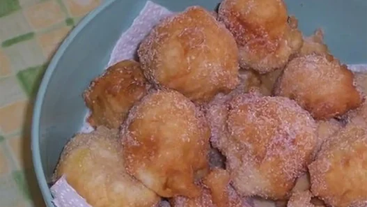 Piatto di frittelle di mele dorate spolverate con zucchero a velo su tavolo di legno