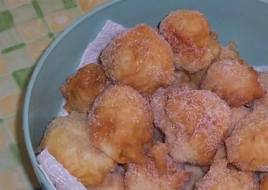 Piatto di frittelle di mele dorate spolverate con zucchero a velo su tavolo di legno