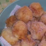 Piatto di frittelle di mele dorate spolverate con zucchero a velo su tavolo di legno
