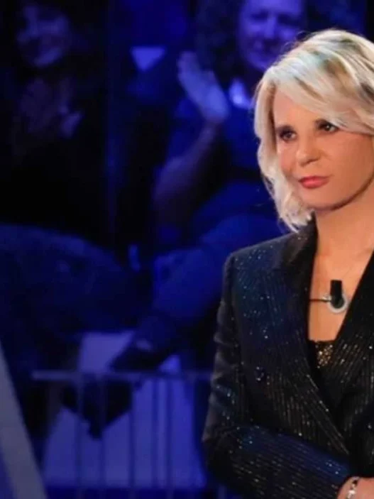 Maria De Filippi sorridente in studio con la busta di C'è Posta per Te