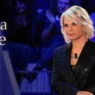 Maria De Filippi sorridente in studio con la busta di C'è Posta per Te