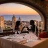 Tavolo apparecchiato per due a lume di candela con vista panoramica in un ristorante romantico italiano.