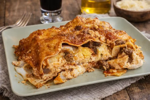 Un piatto di Lasagna di Carnevale con un bicchiere di vino accanto