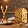 Una fetta di panettone accanto a due candele incrociate, simbolo della benedizione di San Biagio