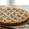Primo piano di una fetta di Torta di San Biagio con ripieno scuro di mandorle e cioccolato e decorazione a losanghe.