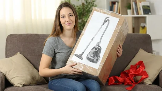Una donna che scarta come regalo un'aspirapolvere