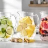 Tre caraffe di vetro con fresche acque detox fai da te a base di frutta e verdura, ideali contro la pancia gonfia post ferie