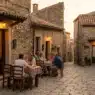 Turisti che cenano all'aperto in una trattoria economica in un borgo italiano nascosto durante il tramonto.