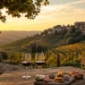 Vista panoramica su un borgo italiano circondato da vigneti, la meta perfetta per un weekend di settembre in un agriturismo immerso nella natura. Descrizione Immagine: Un paesaggio collinare italiano al tramonto che ispira relax e