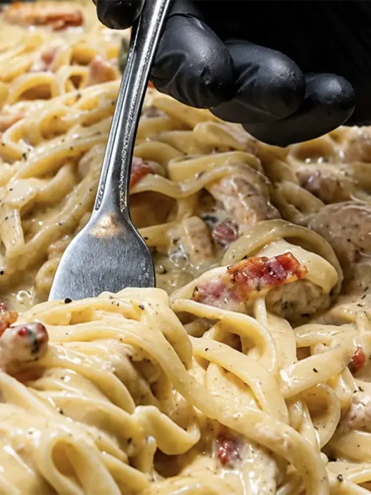 Un piatto di Carbonara chetogenica fumante con Shirataki noodles, guanciale croccante e crema di uova e pecorino.