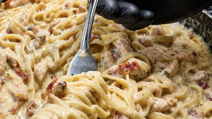 Un piatto di Carbonara chetogenica fumante con Shirataki noodles, guanciale croccante e crema di uova e pecorino.