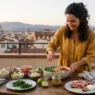 Donna prepara una cena fresca senza cottura con bowl vegetariana e carpaccio di fichi e prosciutto su un balcone al tramonto