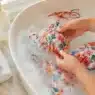 Un costume da bagno colorato in ammollo in una bacinella d'acqua fredda con sapone delicato, il metodo migliore per lavare i costumi ed eliminare la salsedine.