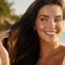 Donna sorridente con capelli lunghi, sani e lucenti. Il risultato dei 3 prodotti per riparare i capelli rovinati da sole e mare