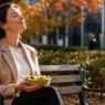 Donna che pratica mindfulness in pausa pranzo al parco, lontana dal PC, per rilassare gli occhi e la mente.