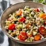 Ciotola colorata con insalata di orzo estiva, verdure e feta, ideale per una ricetta da pranzo veloce.
