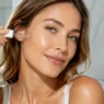 Donna che applica un siero illuminante alla Vitamina C per contrastare le macchie solari sul viso.