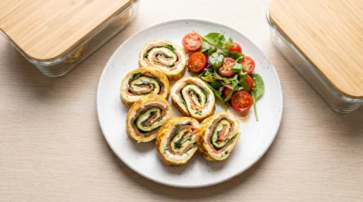Girelle di frittata sottile farcite con salmone affumicato e formaggio spalmabile, disposte su un piatto bianco.
