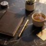 Agenda chiusa e ruota astrologica dorata su marmo scuro, simboli dell'oroscopo dell'11 settembre 2026.